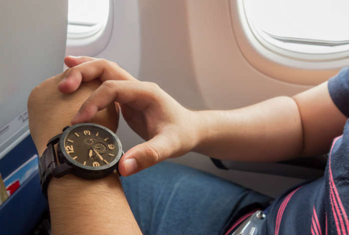 Ilustrasi orang memakai jam tangan GMT di pesawat